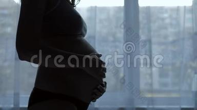 孕妇的剪影<strong>抚摸</strong>着她的胃，<strong>抚摸</strong>着窗户