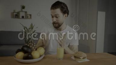 年轻人坐在一张桌子上，在一盘水果、果汁和汉堡包上，一个人正在枯萎有用的产品。 人类发展报告视频