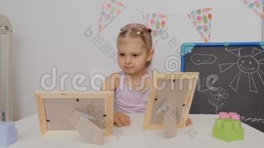 小可爱坐在孩子们的桌子旁`看着相框里的照片