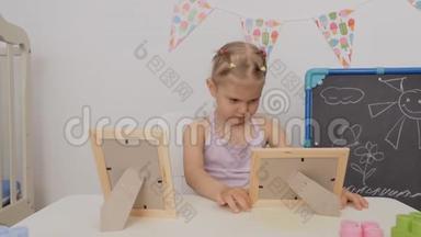 小可爱坐在孩子们的桌子旁`看着<strong>相框</strong>里的<strong>照</strong>片