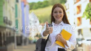 快乐的女高中<strong>学生</strong>，带着背包和书，竖起<strong>大拇指</strong>