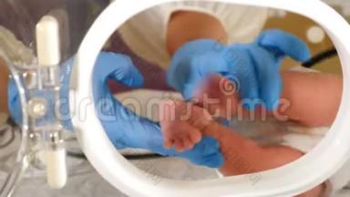 急诊科的<strong>新生儿</strong>。 戴蓝色手套的医生触摸和抱着婴儿的脚<strong>躺</strong>在孵化室里
