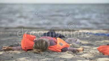 穿救生衣的小女孩躺在海滨，自然灾害的幸存者