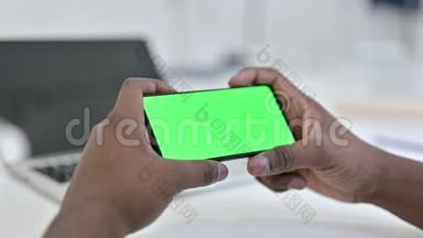 非洲男子手在绿色智能手机屏幕上观看视频