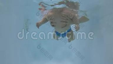 快乐的宝宝在游泳池的水下潜水.. 宝贝学习游泳。 未编辑的水下录像。