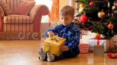 4k视频：小可爱男孩坐在圣诞树旁边的地板上，打开圣诞<strong>老人送礼物</strong>的盒子