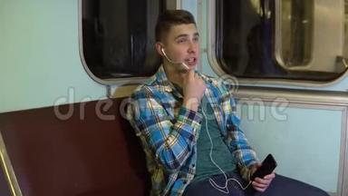 一个年轻人在地铁列车上通过耳机打电话。 旧地铁车