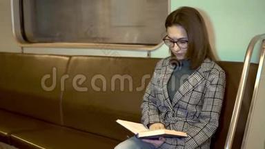 一位年轻女子<strong>正在</strong>地铁火车上<strong>看书</strong>。 旧地铁车
