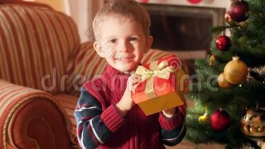 4k视频快乐的笑着小男孩带着圣诞礼物站在漂亮的盒子里看圣诞树