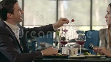 帅哥在浪漫的晚餐上喂女人。 一对浪漫的约会对象