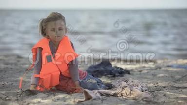 孤独的儿童<strong>难民</strong>穿着救生衣坐在岸边，危险地跨海迁徙