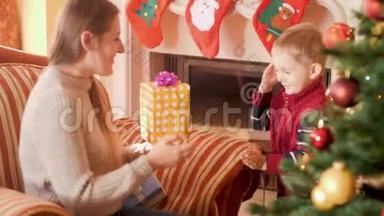 4k<strong>视频</strong>快乐微笑的小男孩把圣诞礼物盒配丝带送给<strong>圣诞树</strong>旁的妈妈