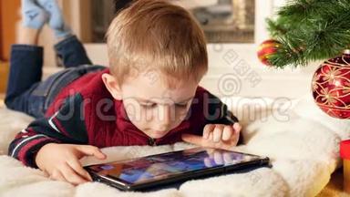 特写4k视频，微笑的小男孩在<strong>数码</strong>平板电脑上玩游戏，同时躺在<strong>家</strong>里的塔姆树下