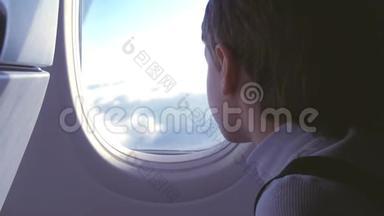 飞机着陆时，男孩嚼着口香糖，看着窗外的云彩。