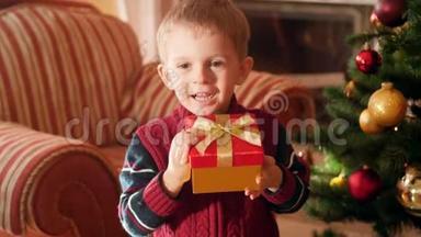 4K镜头，快乐快乐的小<strong>男孩</strong>穿着<strong>毛衣</strong>，手里拿着红色圣诞礼物盒和金色的里本，看着里面