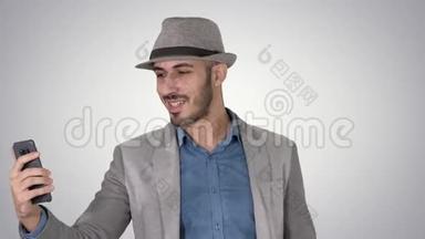 有魅力的男人穿着休闲服装，帽子，时髦的风格，记录<strong>vlog</strong>，或在渐变背景下打视频电话。