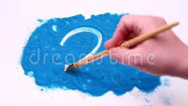 在蓝色的艺术沙滩上，男人手上写着二号。 在白色背景下拍摄的录像。