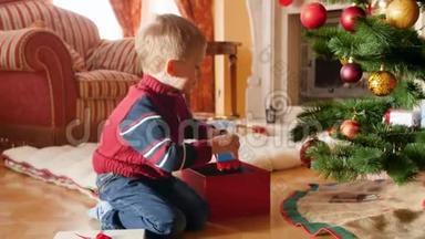 小男孩在圣诞树下的漂亮礼品盒中<strong>包装</strong>玩具的4k视频。 <strong>儿童</strong>赠送礼物和礼物
