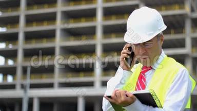 <strong>施工</strong>工程师穿着衬衫，系着<strong>安全</strong>帽和背心在<strong>施工</strong>现场工作，打电话。 人的概念