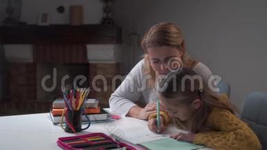 年轻的高加索母亲和她可爱的女儿做家庭作业。 小聪明的女孩写<strong>作业本</strong>妈妈