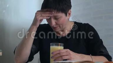 一个穿着黑色<strong>衣服</strong>的女人坐在一张桌子旁，拿着一杯水和维生素来进行大脑活动。 <strong>创意</strong>疲劳