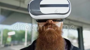 使用虚拟现实耳机进行360VR体验，并带着微笑在户外的眼镜，为年轻大<strong>胡子男士</strong>提供特写