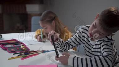 两个白人<strong>孩子</strong>坐在学校的桌子旁。 有两个马尾辫的<strong>女孩子</strong>在练习本上写字