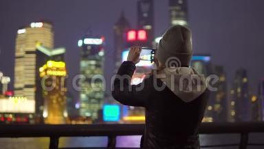 一个穿着黑色夹克和帽子的年轻女孩用手机拍下了上海`景点的照片
