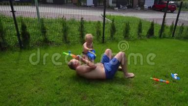小男孩给躺在草坪上的父亲倒水。 夏日炎炎打水仗