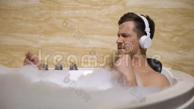 戴耳机的活跃男人用泡沫洗澡，并随着<strong>音乐</strong>节奏移动