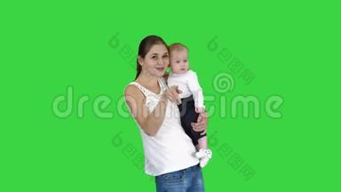 快乐的妈妈和可爱的孩子，宝贝儿子挥舞着双手，在绿色的屏幕上向相机<strong>问好</strong>，色度键。