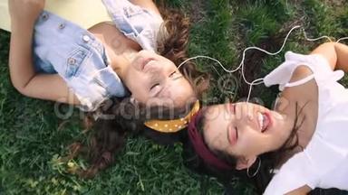 两个女朋友/姐妹<strong>躺在草地</strong>上，听着耳机上的音乐。 两个黑发女人<strong>躺在</strong>公园的<strong>草地</strong>上，