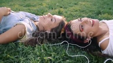 两个女朋友/姐妹<strong>躺在草地</strong>上，听着耳机上的音乐。 两个黑发女人<strong>躺在</strong>公园的<strong>草地</strong>上，