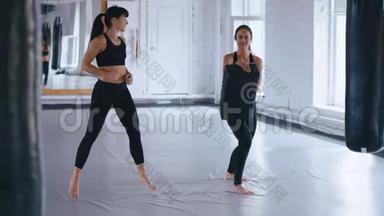 两个身穿黑色健身服的女运动员正在进行一对，<strong>训练</strong>踢腿。 女足运动员<strong>训练比赛</strong>