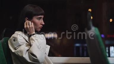 年轻时尚的女人戴着无线耳机，在公共<strong>交通工具</strong>上听手机音乐。 城市