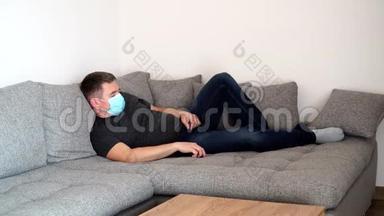 被隔离的冠状病毒男子戴着医疗面具，<strong>很累</strong>，睡在沙发上。 COVID19