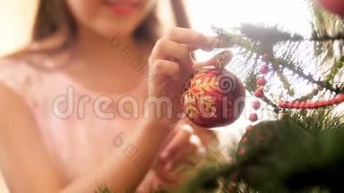 特写4k视频的年轻女子把红色的圣诞树树枝上的饰品。家庭装修