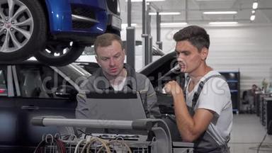 两名汽车修理工在车库用笔记本电脑进行汽车诊断