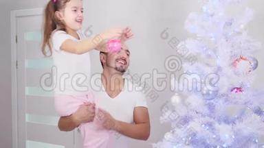 小女儿想把粉红色的宝布尔挂在树的顶端，所以爸爸把她抱起来，孩子做她做的事