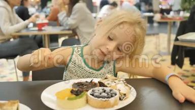 女孩在一个模糊的背景下在咖啡馆里吃各种蛋糕。