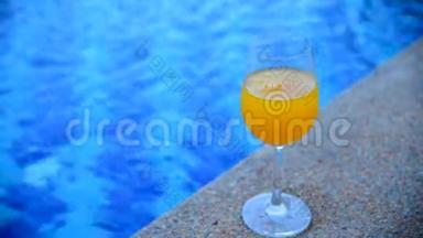 在游泳池的室外，倒入健康的橙汁，以新鲜、美味和甜蜜的软饮料玻璃。 新鲜的橙果园