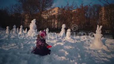快乐的孩子在阳光明媚的冬日堆雪人。