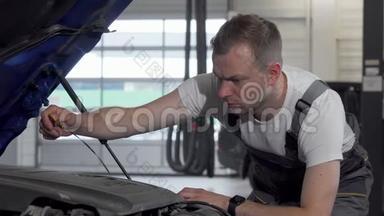成熟的汽车修理工用敞篷汽车检查机油