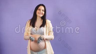 孕妇抱着婴儿小鞋子的肖像。