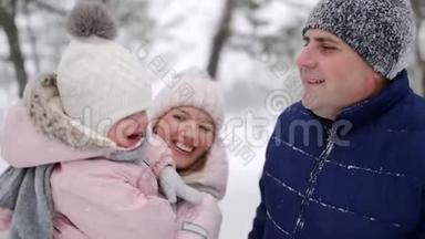 在雪天的<strong>圣诞节</strong>假期，妈妈带着女儿穿连身衣。 穿着<strong>粉色</strong>连衣裙和婴儿一起走路的女人