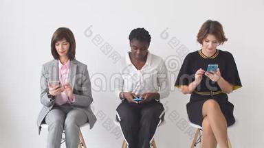 三位商务女士坐在椅子上等着<strong>面试</strong>一家大<strong>公司</strong>的高级职位