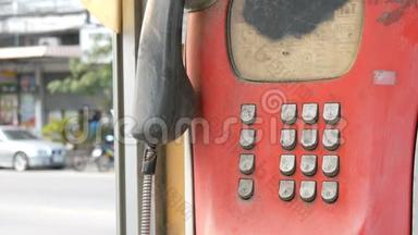 旧的破旧的红色电话设置在一条城市街道上。 电话亭里的老式电话