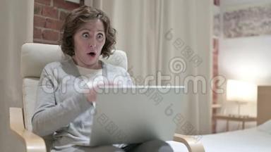 可怜的老女人在沙发上的笔记本电脑上面临着失落