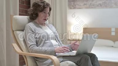 悲伤的老女人面对沙发上的笔记本电脑
