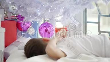 幼儿躺在圣诞树下，摸着球，看着他在<strong>粉红</strong>色玻璃球中的倒影的<strong>视频</strong>。